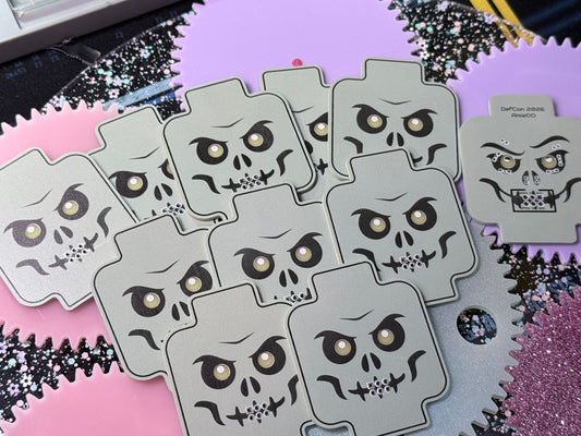 Several unassembled skeleton minifig-inspired DefCon SAO PCBs arranged on a pink and purple background, showing the skull-face artwork and one reverse-side board.